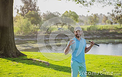 Portrait of happy smilin golfer hitting golf shot with club on course. Stock Photo