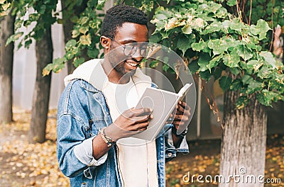 Portrait happy smiling african man reading book in autumn Stock Photo