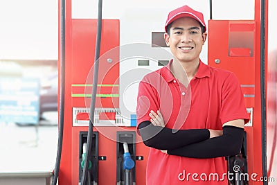 Portrait of happy smiling Asian gas station attendant in red uniform standing with crossed arms at gas station Stock Photo