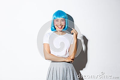 Portrait of happy smiling asian woman in blue shirt wig and shoolgirl costume looking at camera, dressed for halloween Stock Photo