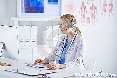 Portrait of a happy smiling young doctor in headset in office Stock Photo