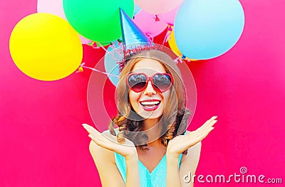 Portrait happy smiling young woman in a birthday cap is having fun over an air colorful balloons pink Stock Photo