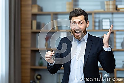 Portrait of a happy and successful realtor broker, the man looks joyfully at the camera and holds the keys to a new Stock Photo