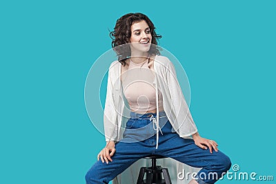 Portrait of happy successful satisfied beautiful young brunette woman in casual style sitting on chair, toothy smiling and looking Stock Photo