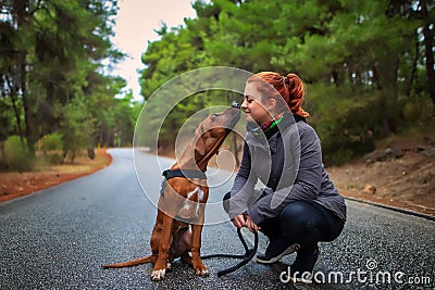 Portrait of happy teenage girl and Rhodesian ridgeback dog . Dog giving girl sweet kiss lick. Stock Photo