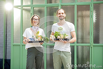 Young couple holding boxes full of fresh raw vegetables outdoors Stock Photo