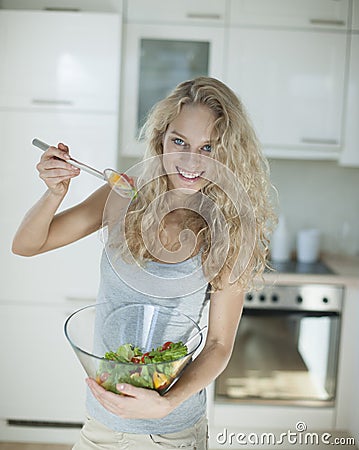 Portrait of happy woman mixing salad in kitchen Stock Photo