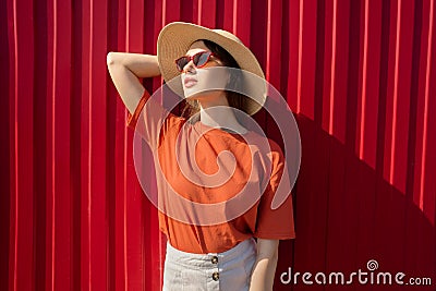 Portrait of a happy woman opposite her red wall. Natural smile. Sunny day. Stock Photo