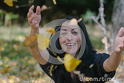 Portrait of a happy woman playing with autumn leaves in forest Stock Photo