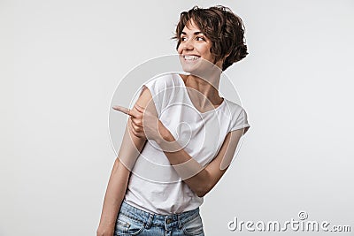 Portrait of happy woman with short hair in basic t-shirt rejoicing and pointing finger at copyspace Stock Photo