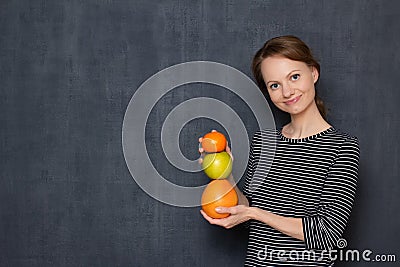 Portrait of happy woman smiling and holding colorful stack of fruits Stock Photo