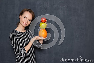 Portrait of happy woman smiling and holding colorful stack of fruits Stock Photo