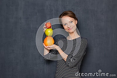 Portrait of happy woman smiling and holding colorful stack of fruits Stock Photo