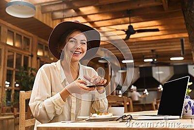 Portrait of happy woman wearing hat photographing food on cell phone Stock Photo