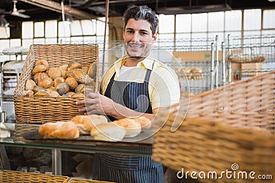 Portrait of happy worker holding basket of bread Stock Photo