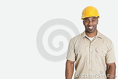 Portrait of happy young African man wearing yellow hard hat helmet over gray background Stock Photo