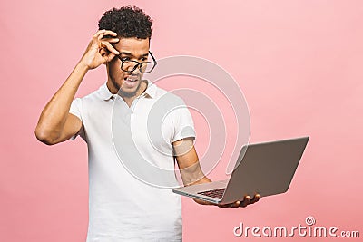 Portrait of happy young afroamerican man using laptop comruter and checkin isolated against pink Stock Photo