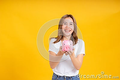 Portrait happy young asian woman holding piggybank saving money for future and business earning income Stock Photo