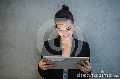 Young business woman with tablet standing against concrete wall in office. Stock Photo