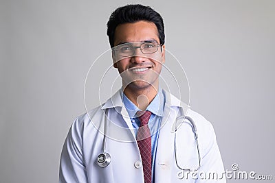 Portrait of happy young handsome Indian man doctor smiling Stock Photo