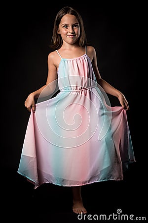 Portrait of happy young little girl holding long colourful dress Stock Photo