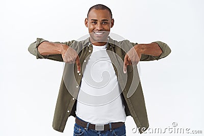 Portrait of happy young male client, african-american man inviting join team, check-out product, pointing fingers down Stock Photo