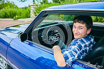 Portrait of happy young man driving blue car Stock Photo