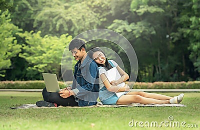 Portrait of a happy young students sitting on the park and using laptop Stock Photo