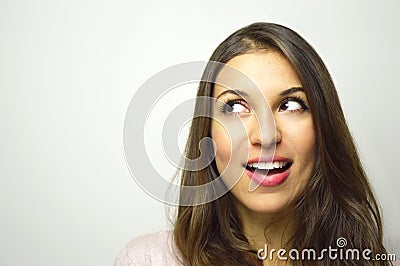 Portrait of happy young woman looking to the side with curiosity on white background. Copy space. Stock Photo