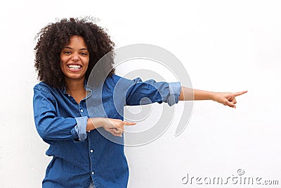 Happy young woman smiling and pointing against white background Stock Photo