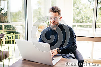 Portrait of happy young writer typing new book on laptop in office Stock Photo