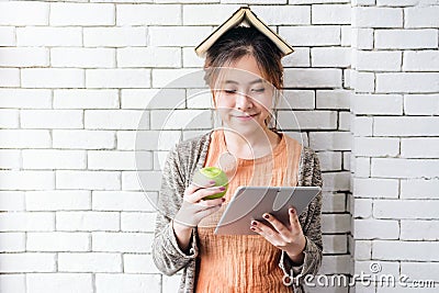 Portrait of healthy young woman holding an apple, book on head w Stock Photo
