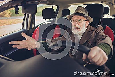 Portrait of his he nice experienced mad annoyed fury furious grey-haired man driving car in traffic jam holding steering Stock Photo