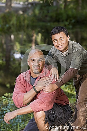 Portrait Hispanic father and son outdoors by pond Stock Photo