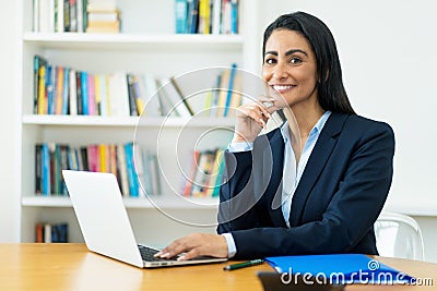 Portrait of hispanic mature businesswoman at computer Stock Photo