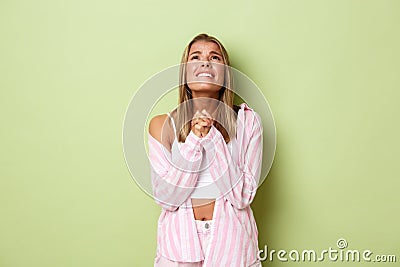 Portrait of hopeful blond woman in pink outfit, pleading God, begging for help and looking up desperate, standing over Stock Photo