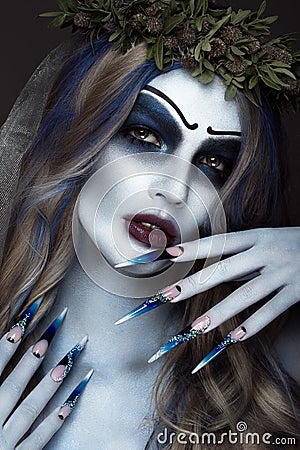 Portrait of a horrible scary Corpse Bride in wreath with dead flowers, halloween makeup and long manicure.Design of Stock Photo