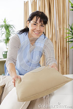 portrait housekeeper tidying sofa Stock Photo
