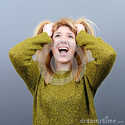 Portrait of a hysterical woman pulling hair out against gray background Stock Photo