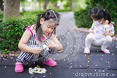 Portrait image child 5-6 years old. Children were sitting with interest collecting flowers that had fallen on ground. Stock Photo