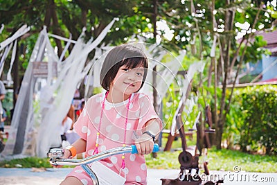 Portrait image child 5-6 years old. Kid riding bicycle on park. Sweet smile. Active girl playing in playground. Stock Photo