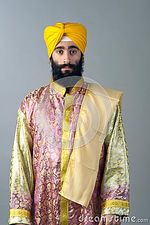 Portrait of Indian sikh man with bushy beard standing against a grey background Stock Photo