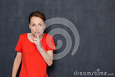 Portrait of indignant girl putting finger up to lips and saying shh Stock Photo