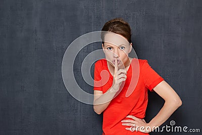 Portrait of indignant girl putting finger up to lips and saying shh Stock Photo