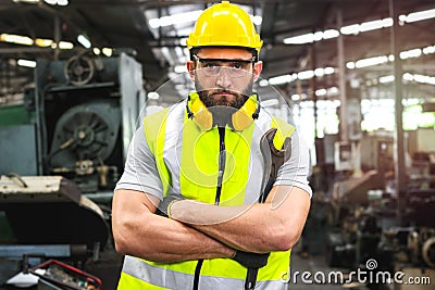 Portrait of industrial engineer worker wearing helmet and safely glasses standing with arms crossed, holding wrench and working at Stock Photo