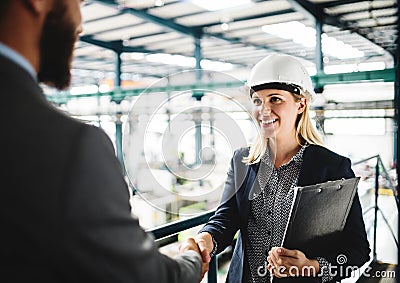 A portrait of an industrial man and woman engineer in a factory, shaking hands. Stock Photo