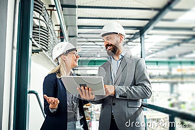 A portrait of an industrial man and woman engineer with tablet in a factory, working. Stock Photo