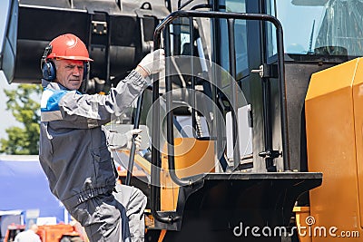 Portrait industrial worker driver in helmet and headphones against background of excavator. People mining concept Stock Photo