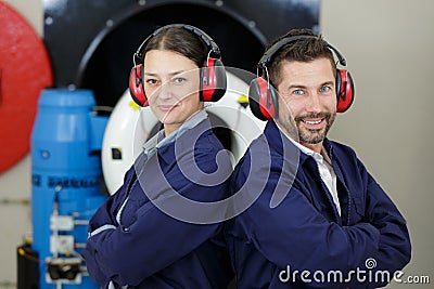 Portrait industrial workers wearing earmuffs standing back to back Stock Photo