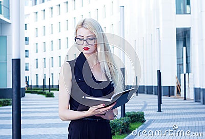 Portrait of an intelligent woman looking to the open notebook on the background of the business center Stock Photo